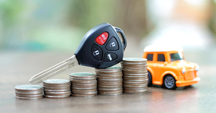 Chave de carro sobre pilha de moedas, representando a situação em que você pode estar pagando juros abusivos em seus empréstimos e financiamentos.