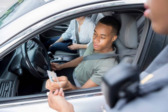 Pessoa com expressão de indignação ao ver seu carro apreendido durante uma blitz, em meio a um processo de busca e apreensão, demonstrando frustração e surpresa com a situação inesperada.